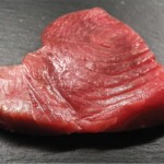 Un steak de thon, prêt à être grillé au feu de bois, par les mains expertes de Gril' Arts et terroir.